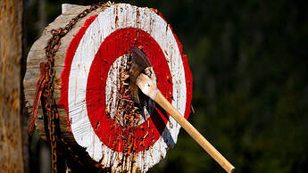 A wooden target with a throwing axe embedded in it