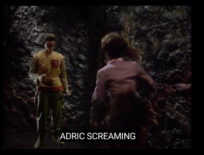 A person in a yellow jacket is seen screaming in a dark, rocky environment with another person running towards them, as indicated by the caption "ADRIC SCREAMING." (Captioned by AI)