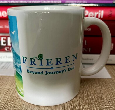 A mug featuring the text "Frieren: Beyond Journey's End" is placed in front of a stack of books. (Captioned by AI)