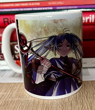 A mug features an illustration of an anime-style character with pointed ears, blue hair, and a sceptre, set against a background of books. (Captioned by AI)